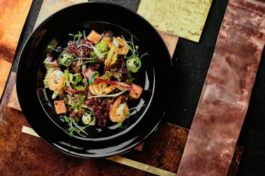 Somonlu salata, karides, marul, salatalık ve soya filizleri bakır tabaklarda siyah bir tabakta. Kapat. en üstteki görünüm