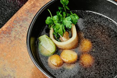 Kemikli şeffaf et suyu, maydanozla süslenmiş ve bakır arka planda siyah bir kasede Brüksel lahanası. Menü için. Bir dizi fotoğraf. yakın plan.