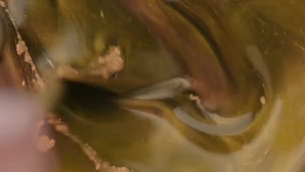 Misturar água com pó de ouro. Whirlpool de água com pó de ouro dissolvido nele. Partículas de tinta dourada fluem na água como o caos colorido. Cosmético natural. Faísca. Preto e dourado. Movimento lento — Vídeo de Stock