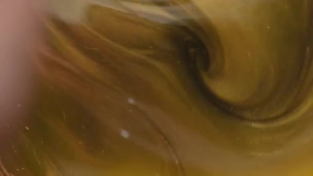 Mixing water with gold dust. Whirlpool of water with gold dust dissolved in it. Particles of gold ink flow in water like colorful chaos. Natural cosmetic. Sparkle. Black and gold. Slow motion — Stock Video