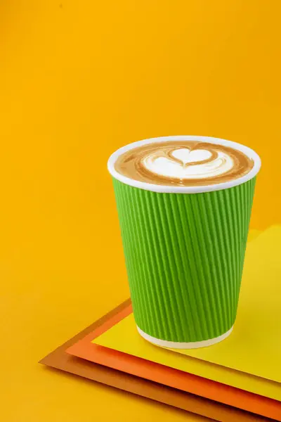 Café Cappuccino en una taza de papel verde sobre fondo amarillo colorido. Burlarse. Café capuchino para llevar. Espacio para el texto. De cerca. — Foto de Stock