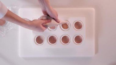 Pasta şefi silikon kek tepsisine krema döküyor. Kremalı tatlı pişiriyorum. Üst görünüm