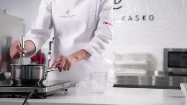 Chef mistura os ingredientes com uma vassoura na cozinha luminosa e espaçosa. chef de pastelaria faz mousse — Vídeo de Stock