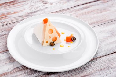 Açık ahşap bir zeminde beyaz bir tabakta piramit şeklinde güzel beyaz bir tatlı. Metin için boşluk