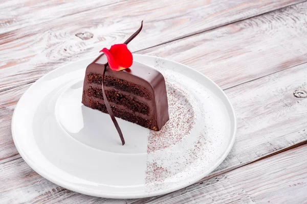 Açık ahşap arka planda beyaz bir tabakta güzel bir mini çikolatalı pasta. Menü ve site için fotoğraf.