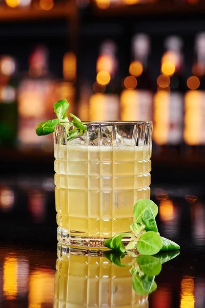 Красивый желтый коктейль со льдом, украшенная капуста пак чой в огранённом стекле на барной стойке в ресторане — стоковое фото
