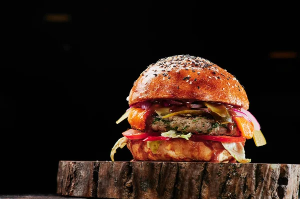 Marha burger sajttal, paradicsommal, vöröshagymával, uborkával és salátával, fekete alapon vágva. Helyet a szövegnek. Egészségtelen élelmiszer. — Stock Fotó