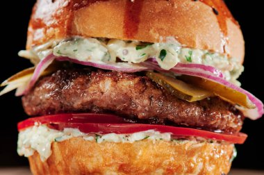 Peynirli sığır burger, domates, kırmızı soğan, salatalık ve marul. Kapatın. Sağlıksız yiyecekler