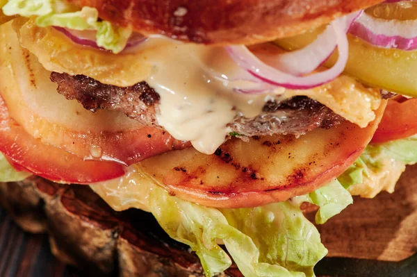Beef burger with cheese, grill vegetables, tomatoes, red onions and lettuce Close up. Unhealthy food. Stock Image