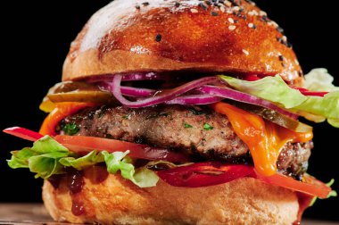 Peynirli sığır burger, domates, kırmızı soğan, salatalık ve marul. Hamburger menüsü. Mesaj için yer var. Sağlıksız yiyecekler.