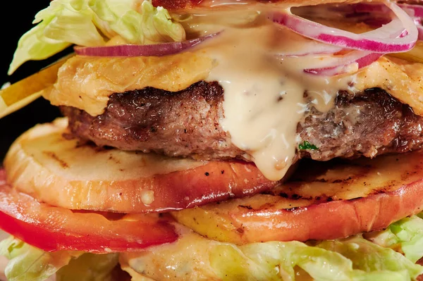 Marha burger sajttal, grill zöldségekkel, paradicsommal, vöröshagymával és salátával Közelkép. Egészségtelen élelmiszer. — Stock Fotó