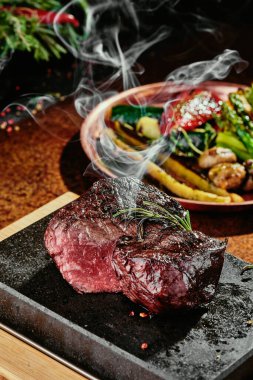 Mayalanmış biftek. Bakır bir çarşafta ızgara sebzeli ızgara biftek. Kapat. seri fotoğraf