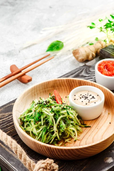 Cibo panasiatico. Insalata di verdure con chuka e cetriolo su piatto di legno su sfondo concreto. Primo piano. Spazio per testo — Foto Stock