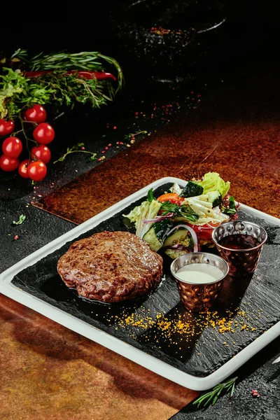 Salatalı ızgara köfte ve bakır kaplama siyah tabakta iki sos. yakın plan
