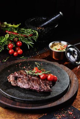 Kızarmış dana filetosu, siyah yuvarlak bir tabakta, bakır bir çarşafın üzerinde. Kapat.