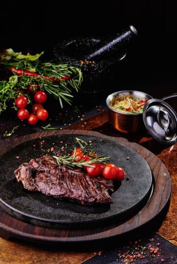 Kızarmış dana filetosu, siyah yuvarlak bir tabakta, bakır bir çarşafın üzerinde. Kapat.