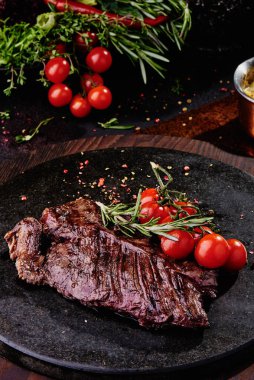 Kızarmış dana filetosu, siyah yuvarlak bir tabakta, bakır bir çarşafın üzerinde. Kapat.