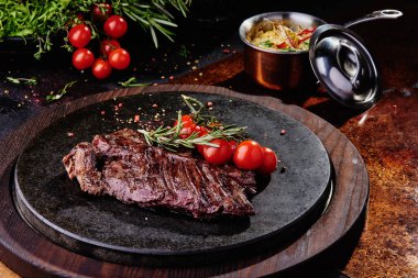 Kızarmış dana filetosu, siyah yuvarlak bir tabakta, bakır bir çarşafın üzerinde. Kapat.