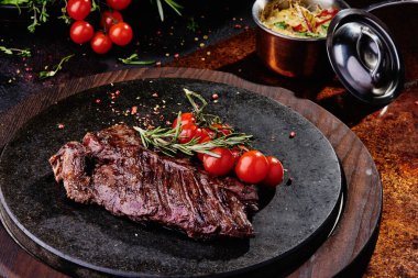 Kızarmış dana filetosu, siyah yuvarlak bir tabakta, bakır bir çarşafın üzerinde. Kapat.