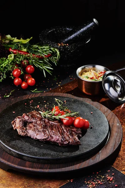 Kızarmış dana filetosu, siyah yuvarlak bir tabakta, bakır bir çarşafın üzerinde. Kapat.