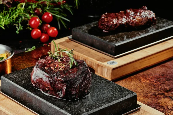 Grilovaný steak. Filet Mignona na černém talíři na pozadí zeleně, koření a zeleniny, na měděném plechu. zavřít — Stock fotografie