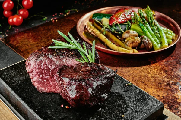 Kvašený steak. Grilované steakové médium s grilovanou zeleninou na černém podnose na měděném podkladu. Zblízka. série fotografií — Stock fotografie