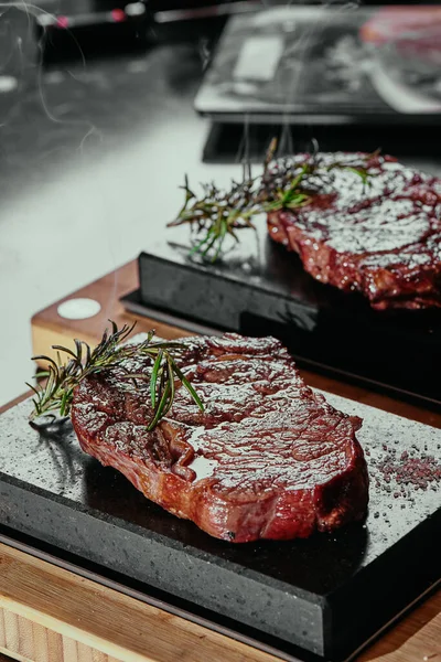 Filete fermentado. Filetes de Ribeye en placas cuadradas de piedra negra. De cerca. fondo oscuro —  Fotos de Stock