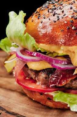 Peynirli sığır burger, domates, kırmızı soğan, salatalık ve marul. Kapatın. Sağlıksız yiyecekler