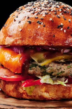 Peynirli sığır burger, domates, kırmızı soğan, salatalık ve marul. Kapatın. Mesaj için yer var. Sağlıksız yiyecekler.