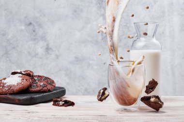 Şeffaf bardakta sütlü kahve. Çikolatalı kurabiye ve arka planda bir bardak süt. Metin için boşluk