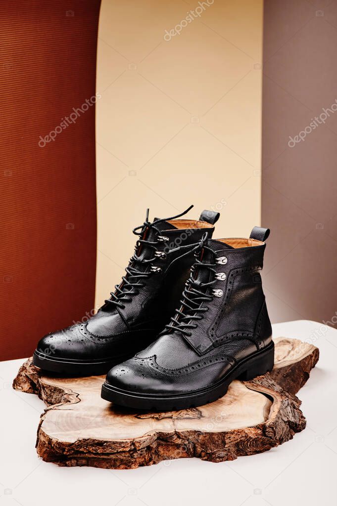 Black leather womens boots made of genuine leather in a classic style on a wooden cut. Close-up. 