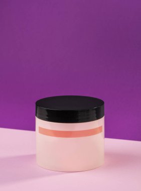 Pembe arka planda siyah kapaklı pembe plastik krema kavanozu. Model modeli. Yakın plan.