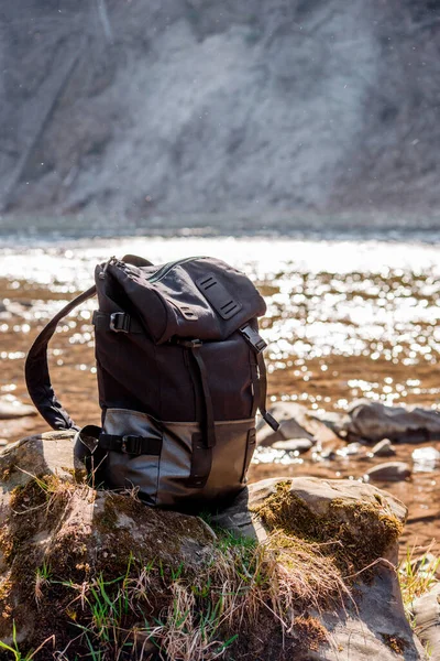 Sports black backpack on the nature by the river. Hiking in the mountains with a backpack.