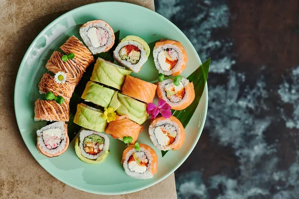 Sushi ensemble avec Philadelphie, rouler avec avocat et rouler avec thon sur plaque verte sur fond d'oxydation. Vue de dessus. Gros plan — Photo