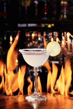 Limonlu Martini kokteyli. Bakır tabaklarda güzel bir bardakta, ateşin arka planında. Kapat.