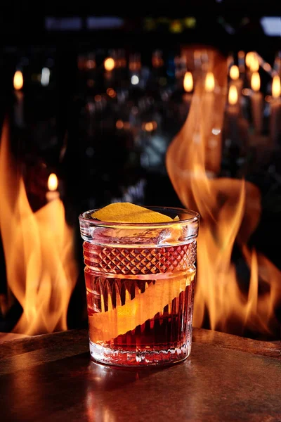 Коктейль Негрони в красивом стекле на медном дизайнерском барной стойке, на фоне настоящего огня. Серия фотографий. — стоковое фото