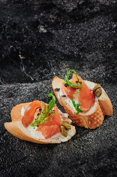 Bruschetta with cream cheese and salmon on textured dark background. Space for text — Foto de Stock
