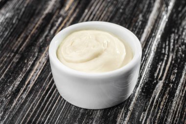 Koyu ahşap arka planda sos kabında beyaz sos. mayonez.