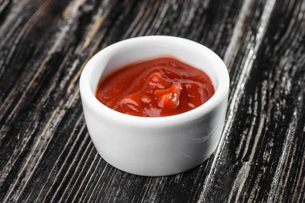 Salsa roja en un bote de salsa sobre un fondo de madera oscura. salsa barbacoa — Foto de Stock