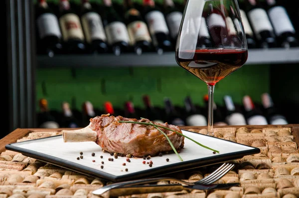 Juicy steak or Rack of lamb and glass of red wine on the background in wine bottle racks