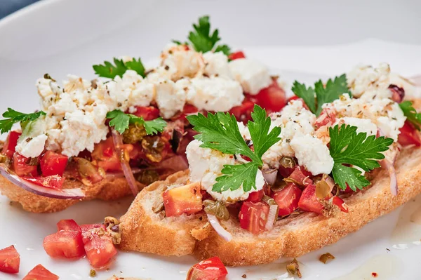 Hermosa bruschetta con queso feta y tomates en un plato blanco de cerca. Espacio para texto — Foto de Stock