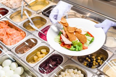 Showcase salad bar with an assortment of ingredients for healthy and dietary food. Salad making process