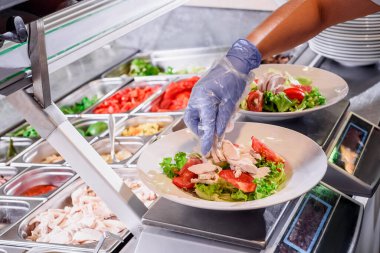 Chef prepares salad at the salad bar. Salad making process. Showcase salad bar with an assortment of ingredients for healthy and dietary food