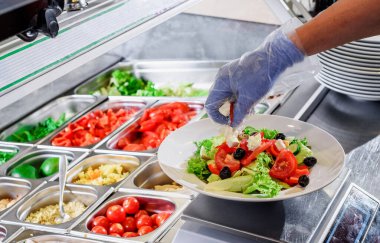 Chef prepares salad at the salad bar. Salad making process. Showcase salad bar with an assortment of ingredients for healthy and dietary food