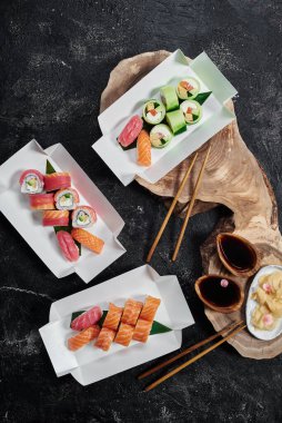 Set of sushi rolls Philadelphia in disposable paper boxes on wooden cut. Delivery service concept. Japanese food in eco-container. Top view. Waste-free packaging