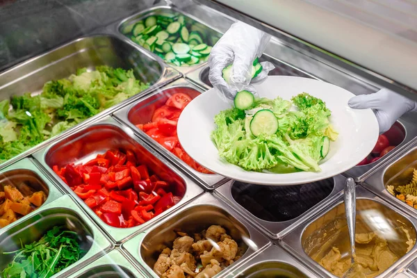 Showcase salad bar with an assortment of ingredients for healthy and dietary food. Salad making process — Fotografia de Stock