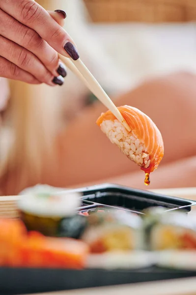 Женщина ест суши с лососем. Суши с лососиной в соевом соусе — стоковое фото