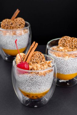 Siyah arka planda izole edilmiş şeffaf bir bardakta meyveli puding. Metin için boşluk