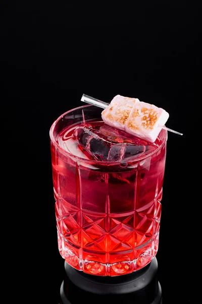 Κόκκινο κοκτέιλ πάγου διακοσμημένο με marshmallows σε όμορφο ποτήρι απομονωμένο σε μαύρο φόντο. Χώρος για κείμενο — Φωτογραφία Αρχείου