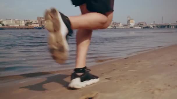 晴れた日に市内のビーチを走る筋肉質の若い男。心臓運動だ。トラッキングカメラ — ストック動画